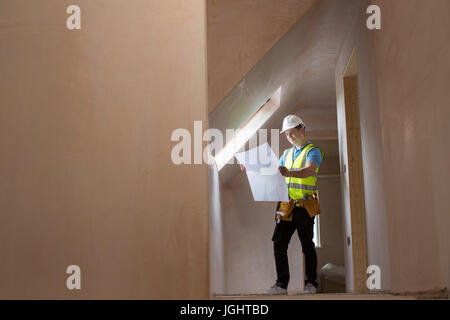 Architect On Building Site Looking At House Plans Stock Photo