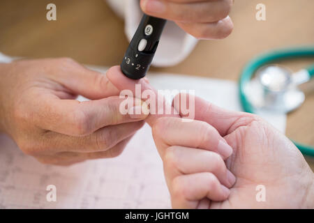 Doctor In Surgery Checking Blood Sugar Level Stock Photo