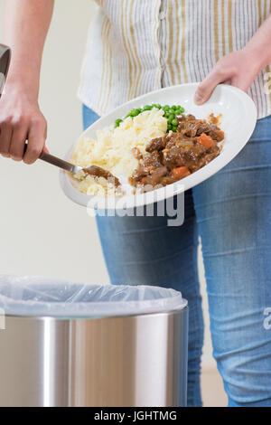 Woman Scraping Food Leftovers Into Garbage Bin Stock Photo