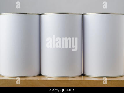 Conceptual image of three tin cans with blank white paper labels on a shelf, copy space on labels allows inclusion of appropriate text or images to in Stock Photo