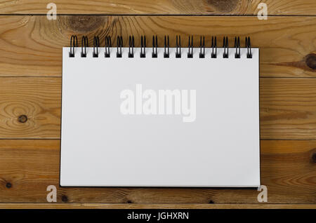 Overhead shot of a spiral notebook, opened on a blank page on wood planked background. Stock Photo