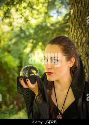 Woman in dark dress with crystal ball in the forest Stock Photo