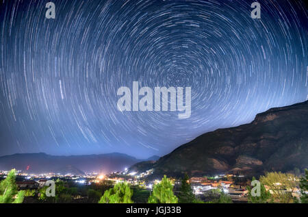 Long exposure image showing star trails over a village in Swat Valley, Pakistan. Stock Photo