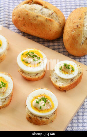 Hard boiled omega 3 organic egg slices on whole grain baguette with mayonnaise and chives in vertical format Stock Photo