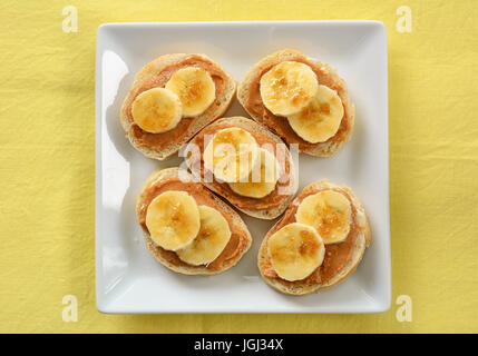 Peanut butter and banana open face sandwiches on square white plate shot in natural light in horizontal format Stock Photo