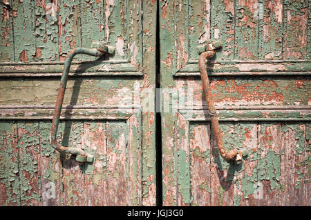 Close-up of two rusty door handles on an old and decrepit wooden barn door with peeling paint Stock Photo
