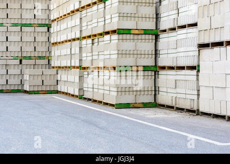 Piles of concrete blocks on wooden pallets stacked outdoors. Stock Photo
