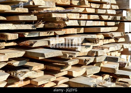 Roughly cut piles of timber planks for home and design construction in sunlight Stock Photo