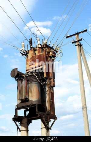 Aged and rusting sub power station with electricity cables and a pylon in the background Stock Photo