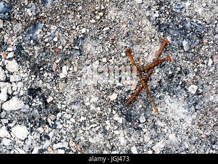 Burnt food can aged with rust sits in the ash remains of a fire Stock Photo