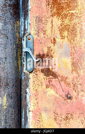 Single locked rusty house door handle set against a deteriorating sheet metal covered in oxidized particles Stock Photo