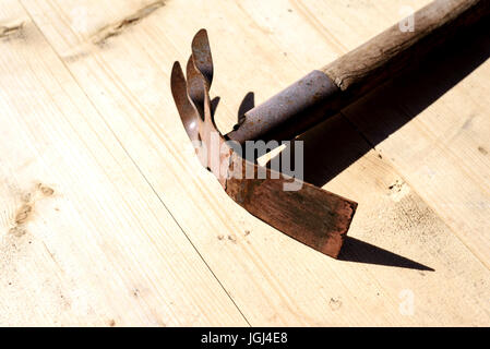 Old rusty vintage retro styled garden hoe on a wooden rustic planks Stock Photo