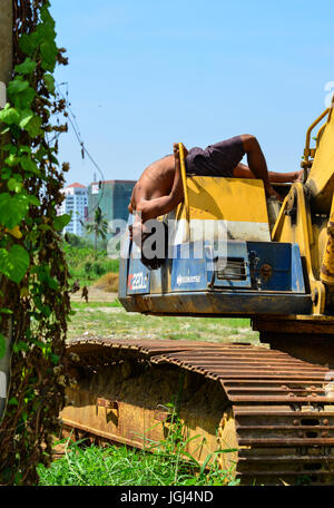 Delhi, India - Mar 9, 2017. An Indian young man doing Yoga exercise on the construction machine at sunny day in Delhi, India. Stock Photo