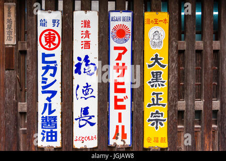 Japan, Tatsuno. Traditional old-fashioned Japanese kanji oblong advert signs for beer and saki on front shutters of old Japanese style store. Stock Photo