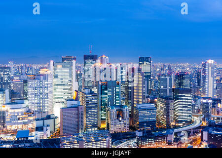 Osaka City, Japan. Night time high angle view from top of Umeda Sky building. High rise office blocks with mountains in the background. Stock Photo