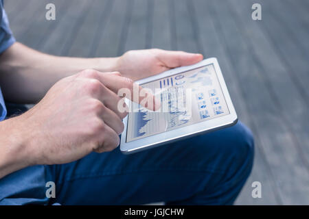 Casual person using digital tablet computer to analyse a financial dashboard with charts and key performance indicators (KPI) for stock market investm Stock Photo