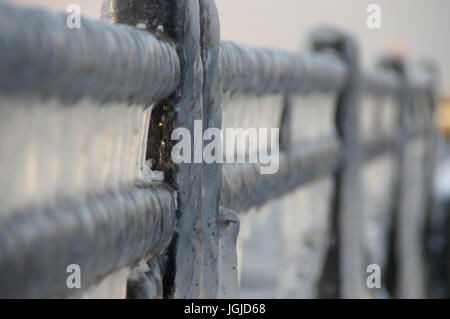 Icicles on metal fence. Ice cover in winter. Stock Photo