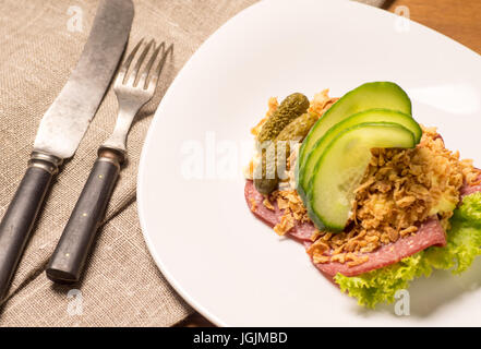 Danish specialties and national dishes, high-quality open sandwich. Salami with crispy onion, remoulade and cucumber served on a plate ready for eatin Stock Photo