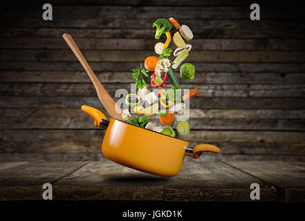 Fresh vegetables flying into a pot, placed on wooden planks Stock Photo