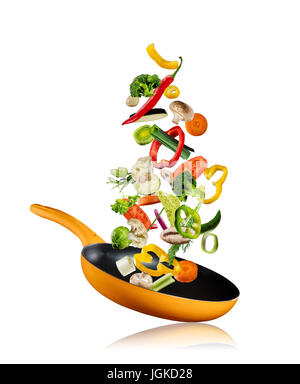 Fresh vegetables flying into a pan, isolated on white background Stock Photo