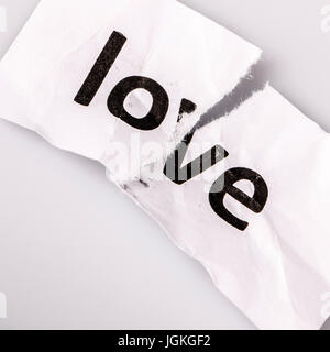 "Love" word written on torn paper on white Stock Photo