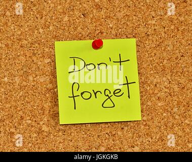 Cork notice board with one yellow sticky note pad with text please do not forget Stock Photo