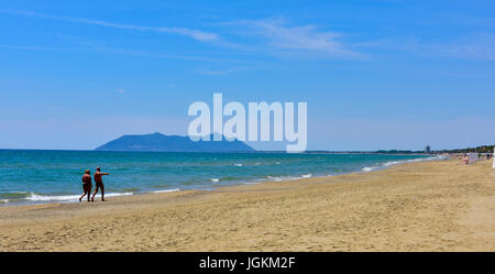 Two people walking along nearly deserted Sandy Mediterranean beach, Italy. Stock Photo