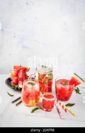 Set of watermelon summer drinks and cocktails: sangria, juice cooler cocktail, infused detox water, watermelon vodka shot. On a white marble table. Co Stock Photo