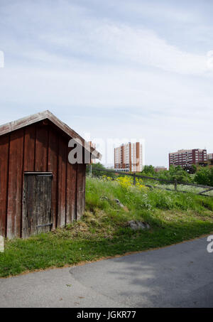 an old-fashioned red painted shed beside a sidewalk with the city rising in the background. Stock Photo