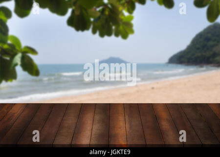 blank wooden shelf with leaf frame on blurry beach and sea. wood stage for showing product on natural background. Stock Photo