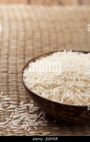 Basmati rice in wooden bowl on straw background Stock Photo