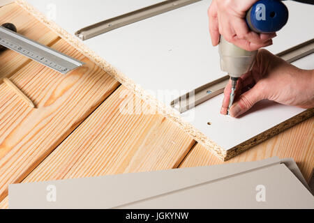 Assembling furniture from chipboard, using a cordless screwdriver, close up Stock Photo