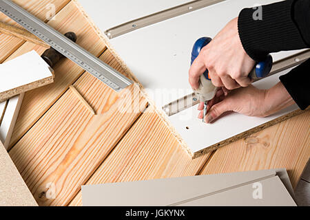 Assembling furniture from chipboard, using a cordless screwdriver, close up Stock Photo