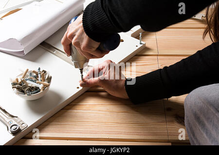 Assembling furniture from chipboard, using a cordless screwdriver, close up Stock Photo