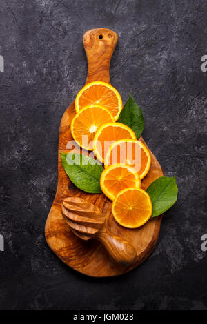 Slices of ripe orange on olive wood cutting board over black slate background.Top view with copy space Stock Photo