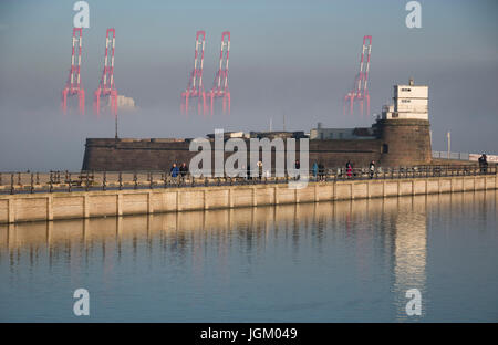Giant dockside cranes at Seaforth container terminal rising out of the mist behind Fort Perch Rock, New Brighton Stock Photo