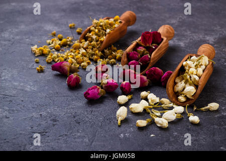 Assortment of dry flower tea in a spoon over black slate stone with copy space. chamomile,rose and jasmine flowers Stock Photo