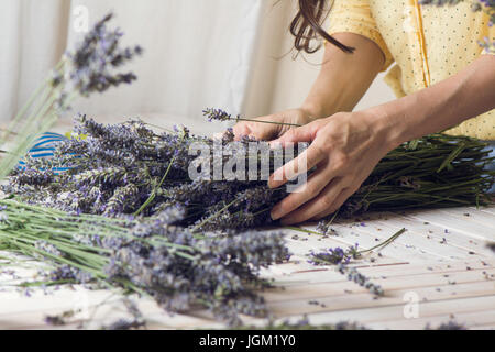 Florist at work: woman creating bouquet of natural lavender flowers, in te wooden table, small business concept. Close-up Stock Photo