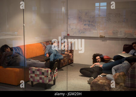 group of young casual software developer sleeping on  sofa during a work break in creative startup office Stock Photo