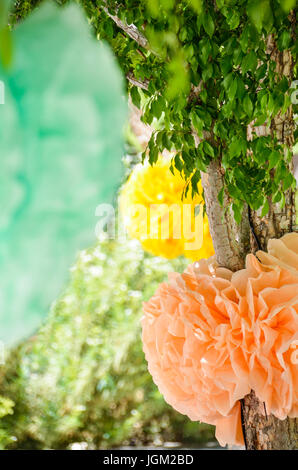 Hanging colorful paper decorations on tree in summer Stock Photo