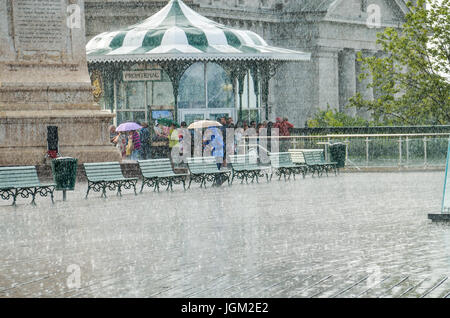 Quebec City, Canada - July 27, 2014: Crowd of people walking in heavy rain on Dufferin terrace boardwalk street close to Chateau Frontenac Stock Photo