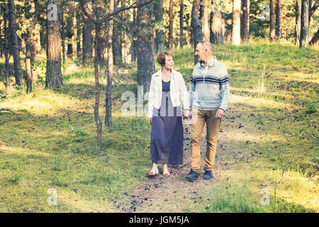senior couple walking on forest trail holding hands Stock Photo
