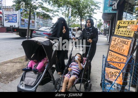 Two Muslim mothers pushing their children up Church Avenue in the highly multi-cultural Kensington neioghborhood of Brooklyn, NY. Stock Photo
