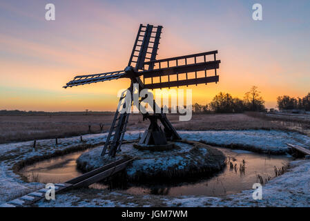 Tsjaker near Kalenberg during sunrise in wintertime with snow, trees and ditch in National Park De Weerribben-Wieden in The Netherlands. Stock Photo