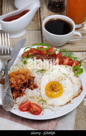 Breakfast - Soft boiled rice with scrambled eggs, bacon, tomato slices and greens Stock Photo