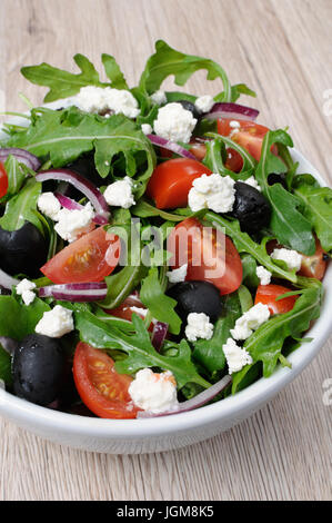 Variation of Greek salad with arugula, cherry slices, feta and olives Stock Photo
