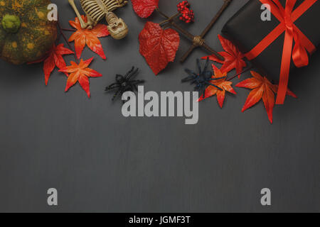 Top view Happy Halloween Holiday background with decoration.The pumpkin handmade,orange forest leaf,skeleton,black gift box and spiders on wooden back Stock Photo