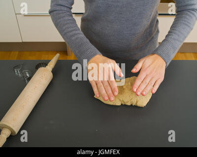 Woman rolls out with a rolling-pin the biscuit dough - woman with rolling pin, baking, Frau rollt mit einem Nudelholz den Keksteig aus - woman with ro Stock Photo