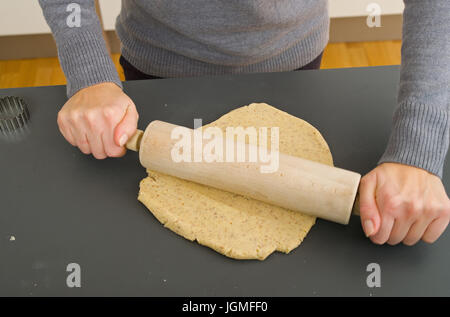 Woman rolls out with a rolling-pin the biscuit dough - woman with rolling pin, baking, Frau rollt mit einem Nudelholz den Keksteig aus - woman with ro Stock Photo