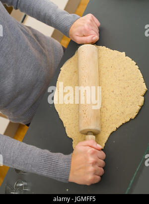 Woman rolls out with a rolling-pin the biscuit dough - woman with rolling pin, baking, Frau rollt mit einem Nudelholz den Keksteig aus - woman with ro Stock Photo